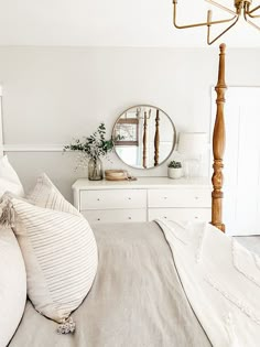 a bed with white sheets and pillows in a bedroom