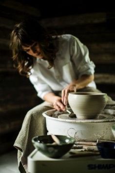 a woman is working on a pottery bowl