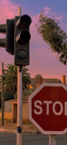 a stop sign and traffic light at an intersection with palm trees in the back ground