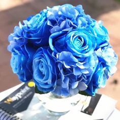 a bouquet of blue flowers sitting on top of a table next to an open book