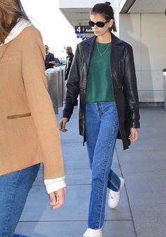 a woman walking down the sidewalk with her hand in her pocket and another person wearing sunglasses