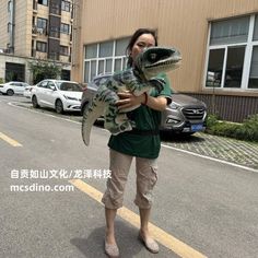 a woman is holding a large alligator in the middle of an empty street with cars parked on both sides