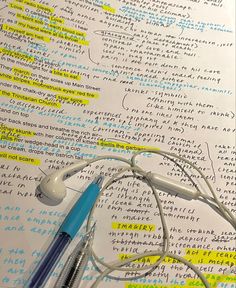 two pens and headphones on top of a book with writing all over it's pages