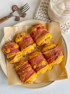 bacon wrapped in cheese on a plate next to utensils