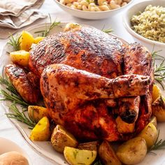 a roasted turkey with potatoes and rosemary garnish sits on a plate next to other dishes