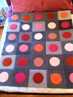 a bed topped with a quilt covered in lots of different colored circles on it's side