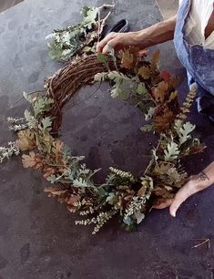 a man is making a wreath out of branches and leaves