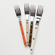 three forks with different colored handles on white surface