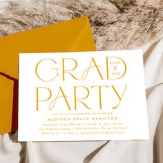 an orange envelope with a white card on it and the words grad party written in gold