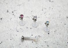 three pairs of ear studs with different colored stones on them sitting next to each other