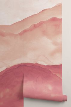 a pink and white wallpaper with an abstract painting on the wall behind it that looks like mountains