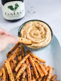 a plate topped with french fries next to a bowl of dip