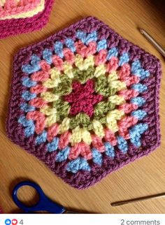 a crocheted square is sitting on a table next to some scissors and yarn