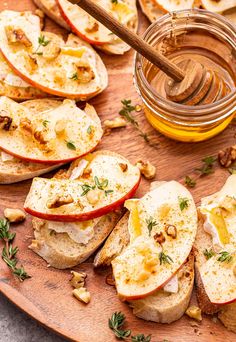 an apple and cheese sandwich on a wooden platter next to a jar of honey