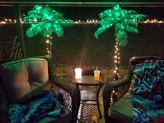 two wicker chairs sitting next to each other on a patio with palm trees in the background