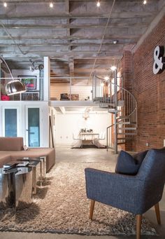 a living room filled with furniture and a spiral stair case next to a brick wall