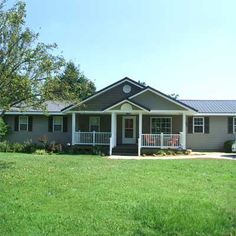 a gray house sitting on top of a lush green field