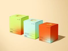 three boxes with different colors on them sitting next to each other in front of a beige background