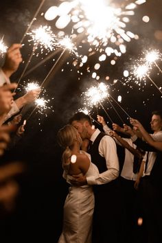 a bride and groom kiss as they are surrounded by sparklers