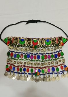 * This traditional classic necklace is an epitome of tradition. The tribal choker statement features three layers, each embellished with multicolour glass stones. * The style of the necklace is inspired by the Kuchi style of ornaments, as adorned with floral motifs and vintage coins dangling at the bottom. * The golden silver hues are complementing the vibrant glass stone inlays and elements at the top and bottom. The tribal necklace is a traditional fashion jewelry statement, festooned with met Traditional Adjustable Necklaces With Colorful Beads, Traditional Adjustable Necklace With Colorful Beads, Traditional Necklaces With Colorful Beads And Adjustable Fit, Handmade Multicolor Jewelry For Traditional Ceremonies, Traditional Green Adjustable Necklace, Traditional Metal Necklaces For Celebrations, Bohemian Jewelry For Traditional Ceremonies, Traditional Necklaces With Colorful Beads For Festivals, Traditional Adjustable Jewelry With Colorful Beads