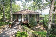 a gazebo sits in the middle of a wooded area with stairs leading up to it