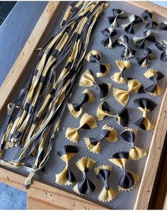 several different types of pasta being made on a baking sheet in a wooden tray with black and white trim