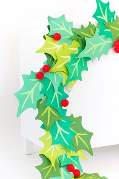 an ornament made out of paper with holly leaves and red berries on it