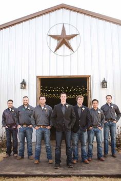 a group of men standing next to each other in front of a barn