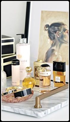 an assortment of women's perfumes on a marble tray with a painting in the background