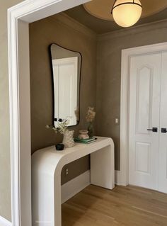 a white table with a mirror on top of it next to two doors and a door way