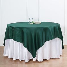 a green and white table cloth on top of a round table with two wine glasses