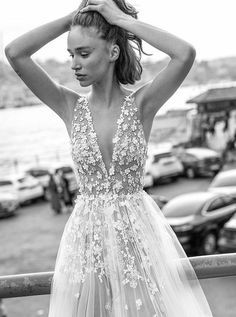 a woman in a dress standing next to a railing with her hands on her head