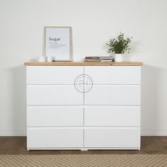 a white dresser with a plant on top of it and a framed photograph next to it