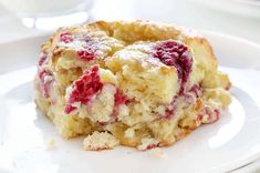 a close up of a piece of cake on a plate with powdered sugar and raspberry topping