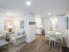 a living room filled with furniture next to a kitchen and dining room table on top of a hard wood floor