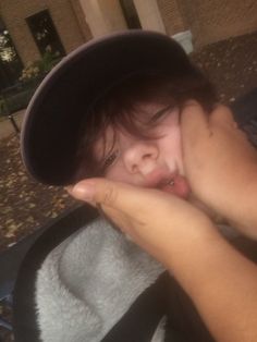 a young boy wearing a hat and sticking his tongue out