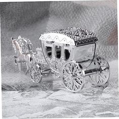 a silver carriage with two horses on the front and side, sitting on a cloth covered surface