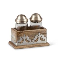 two salt and pepper shakers sitting on top of a wooden box with metal lids