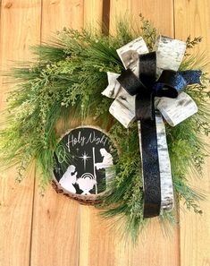 a christmas wreath on a wooden floor with a black and white ribbon tied around it