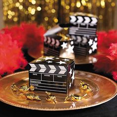 a movie clapper on a gold plate with red flowers and streamers in the background