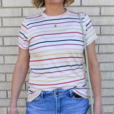 This lightweight rainbow stripe top brings a smile after a rainstorm, or just because! Spring Crew Neck Top With Vertical Stripes, Trendy Vertical Stripes T-shirt For Summer, Trendy Spring T-shirt With Vertical Stripes, Trendy White Top With Vertical Stripes, Trendy T-shirt With Vertical Stripes And Crew Neck, Trendy Crew Neck T-shirt With Vertical Stripes, Striped Crew Neck Top For Day Out, Striped Rainbow Print T-shirt For Spring, Trendy Rainbow Print Striped Tops