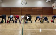 a group of people standing on top of a gym floor with balls in their hands