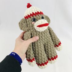 a hand holding up a knitted sock monkey