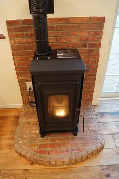 a wood stove sitting on top of a wooden floor next to a brick wall and door