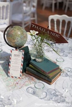 a table topped with books and a globe on top of a white table cloth covered table