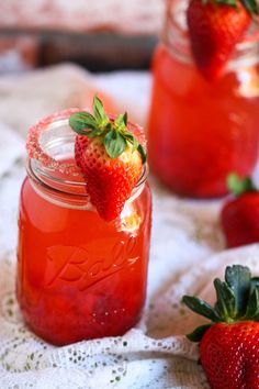 two mason jars filled with strawberry lemonade and garnished with fresh strawberries