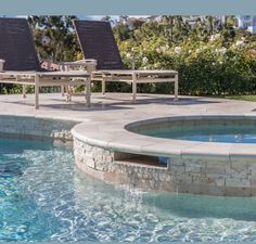 two lounge chairs sitting next to a swimming pool