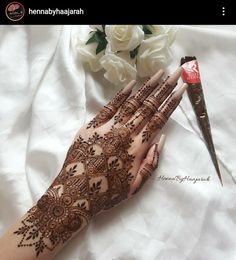 the henna is on someone's hand with a flower bouquet in the background