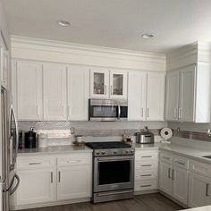 a kitchen with white cabinets and stainless steel appliances