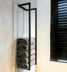 a towel rack in the corner of a bathroom next to a window with shutters